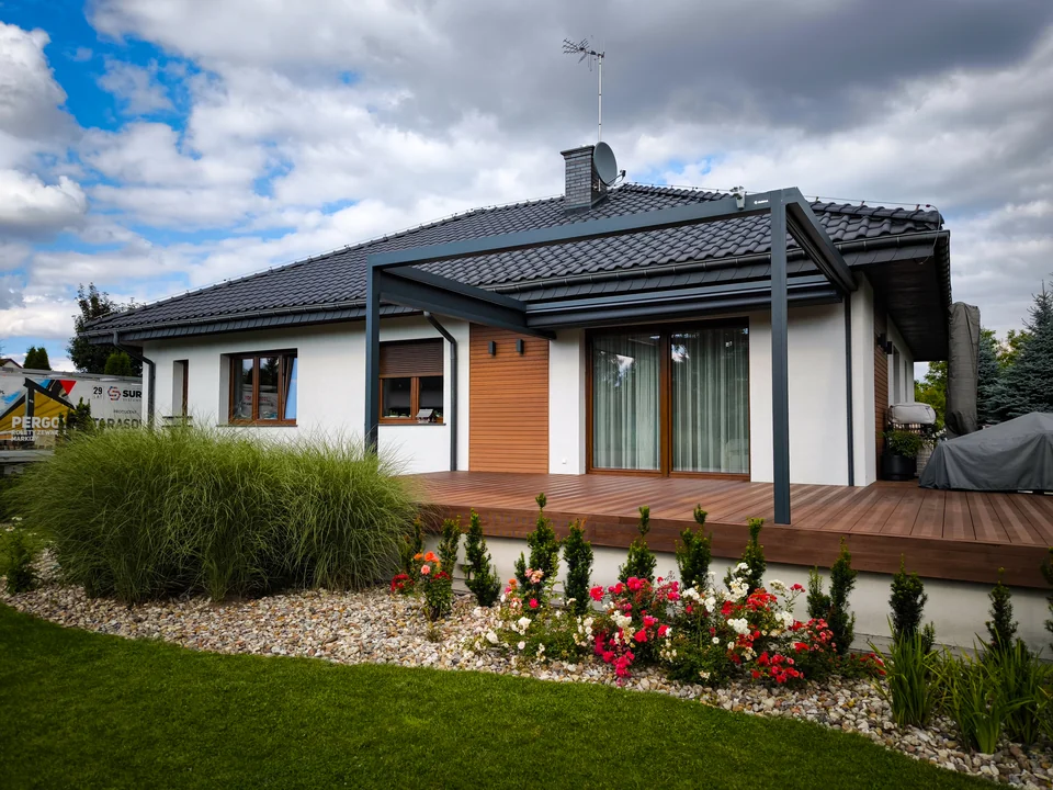 Grafitowa pergola lamelowa wzdłuż tarasu przy parterowym domu