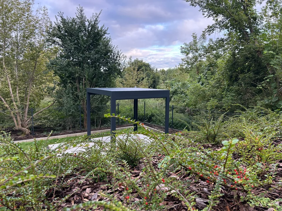 Wolnostojąca pergola na podeście widziana z głębi ogrodu