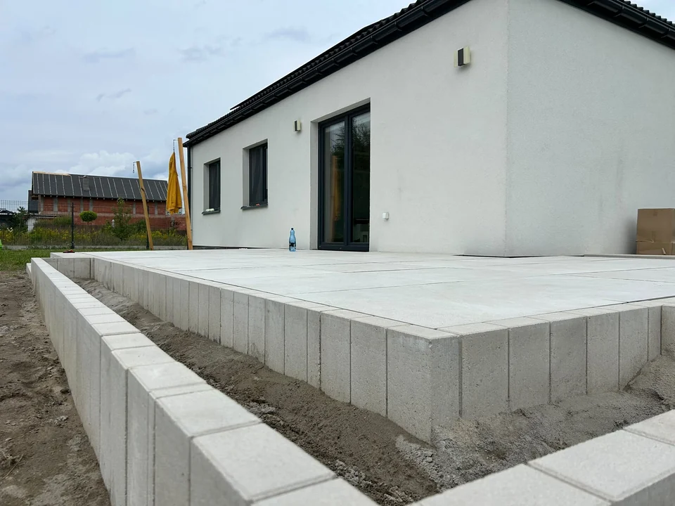 Narożnik jasnego tarasu przy białej elewacji